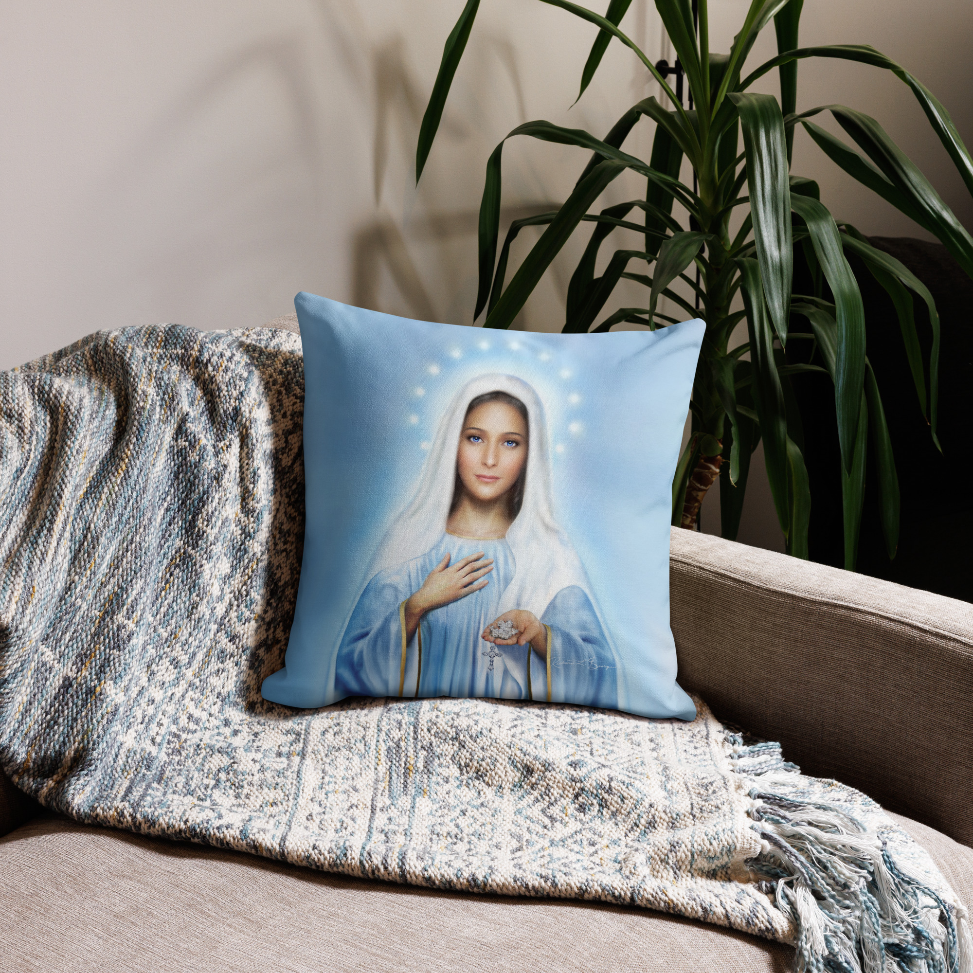 Photo of a pillow with the image of Our Lady of Medjugorje without words on it placed on a couch with a blanket